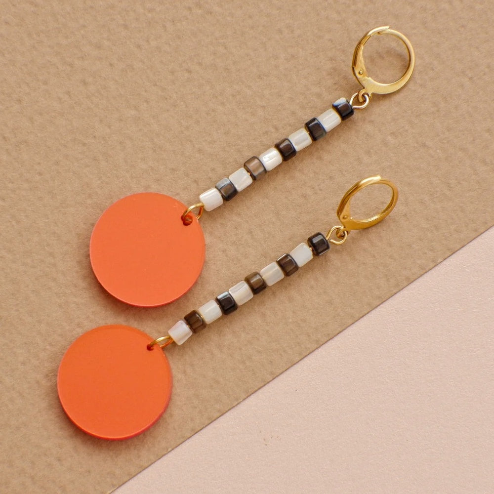 Pendientes con tira en blanco y negro y gran círculo naranja al final de Mitumi