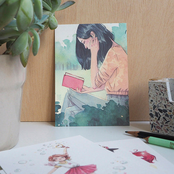 Ilustración de una mujer leyendo en el pack rojo de postales de la ilustradora Esther Gili