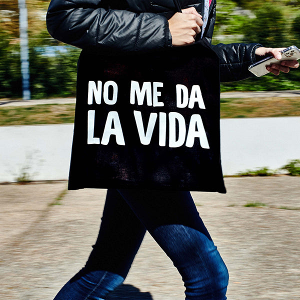Persona con prisa con una bolsa de tela negra con la frase: "No me da la vida"