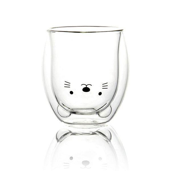 Un vaso de cristal con forma y cara de gato vacío.